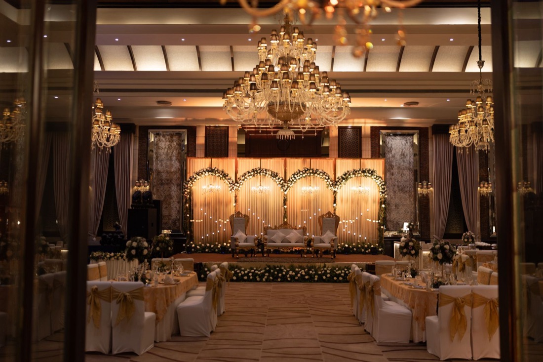 Grand luxury wedding ballroom with crystal chandeliers and a floral stage by Nakshatra Wedding in Chennai